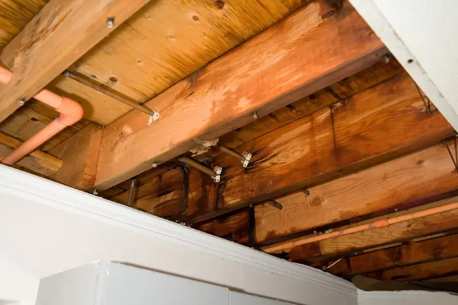 Wet joists and supply pipe exposed after a burst pipe soaked the ceiling below